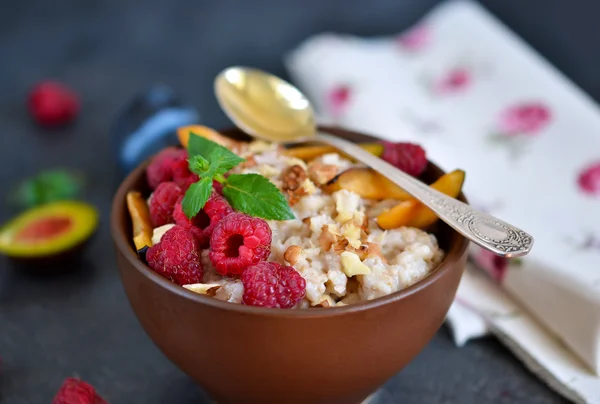 Oatmeal with berries, plums, nuts and honey for breakfast — Stock Photo, Image