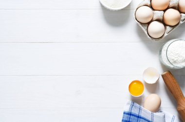 Fırın malzemeleri: un, yumurta, beyaz ahşap zemin üzerinde merdaneli şeker. Kopyalama alanı ile.