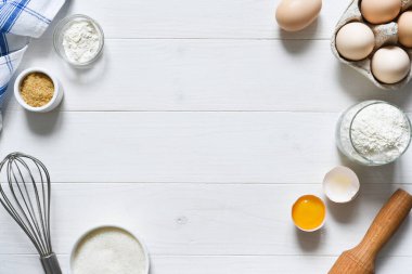 Fırın malzemeleri: un, yumurta, beyaz ahşap zemin üzerinde merdaneli şeker. Kopyalama alanı ile.