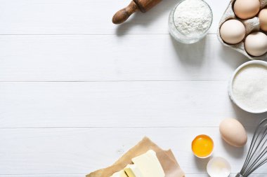 Fırın malzemeleri: un, yumurta, beyaz ahşap zemin üzerinde merdaneli şeker. Kopyalama alanı ile.