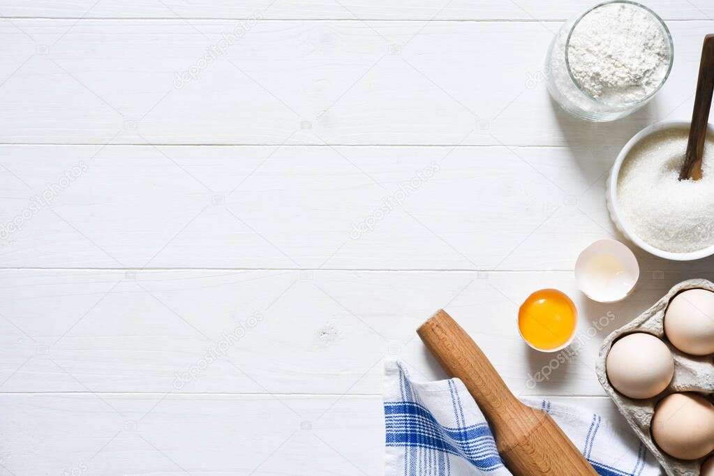 Baking ingredients: flour, eggs, sugar with a rolling pin on a light white wood background. With copy space.