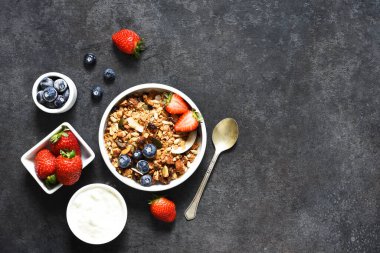 Yoğurtlu granola, siyah arka planda tohumlar ve hindistan cevizi..