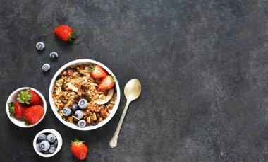 Yoğurtlu granola, siyah arka planda tohumlar ve hindistan cevizi..