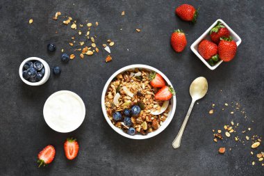 Yoğurtlu granola, siyah arka planda tohumlar ve hindistan cevizi..