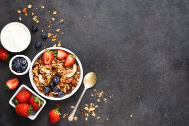 Yoğurtlu granola, siyah arka planda tohumlar ve hindistan cevizi..