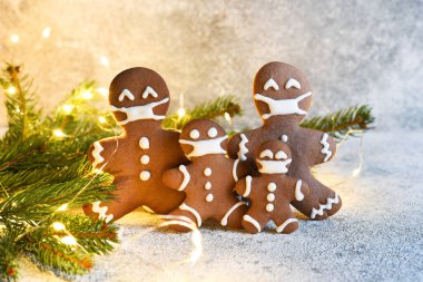 Maskeli zencefilli kurabiye ailesi. Noel arkaplanı. Zencefilli çörek, ladin ve ışık. Karantina.