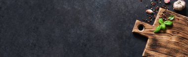 Siyah beton bir masada taze fesleğen ve baharatla tahta kesmek. Kopyalama alanı olan üst görünüm.