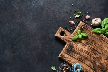 Siyah beton bir masada taze fesleğen ve baharatla tahta kesmek. Kopyalama alanı olan üst görünüm.