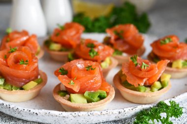 Tartlets with cream cheese, avocado and salmon. Salmon appetizer on the kitchen table.