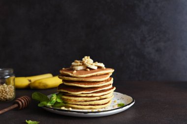 Arka planda muz ve çam fıstıklı ev yapımı krepler.