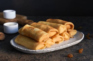 Koyu beton arka planda süzme peynirli ince krepler. Platformlar. Beyaz Rusya ve Ukrayna 'nın ulusal ve geleneksel yemekleri.