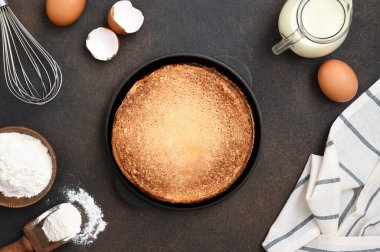 Beton arka planda krep pişirmek, üst manzara. Krep malzemeleri: süt, yumurta, un.