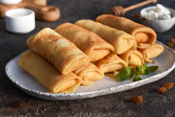 Koyu beton arka planda süzme peynirli ince krepler. Platformlar. Beyaz Rusya ve Ukrayna 'nın ulusal ve geleneksel yemekleri.