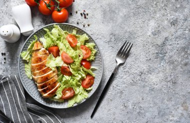 Fırında tavuk göğsü ve çimento kaplı domatesli salata. Sağlıklı yiyecekler, keto diyeti, paleo diyeti. Kopyalama alanı olan üst görünüm.