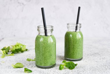 Detoks menüsü. Kavanozda beton bir arka planda ıspanaklı içecek..