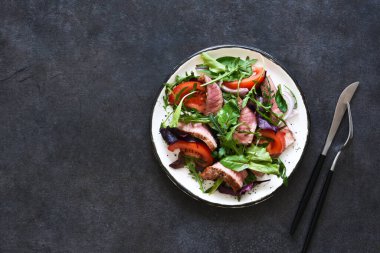 Salatayı domateslerle karıştır ve koyu arkaplanda orta boy sığır eti..