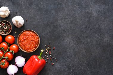 Koyu beton arka planda biberli domates sosu ve sarımsak..