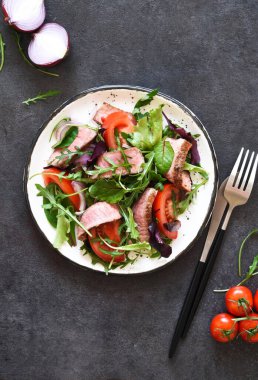 Salatayı domateslerle karıştır ve koyu arkaplanda orta boy sığır eti..