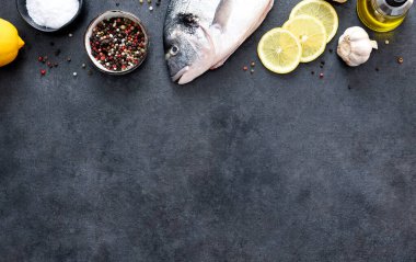 Siyah beton arka planda limon ve baharatlı çiğ dorado..