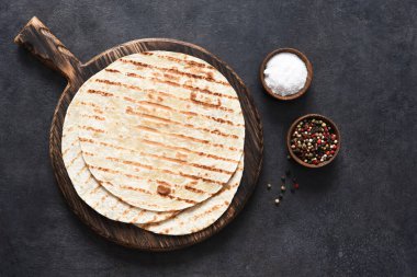Baharatlı ızgara tortilla. Meksika yassı ekmeği - Tahta tahtada siyah beton arka planda tortilla.