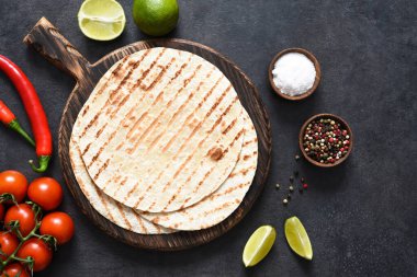 Baharatlı, acılı ve limonlu ızgara tortilla. Meksika yassı ekmeği - Tahta tahtada siyah beton arka planda tortilla.