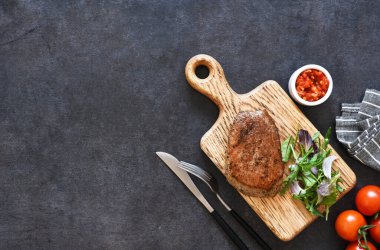 Kızarmış biftek, salata ve ahşap bir tahta üzerinde sos..