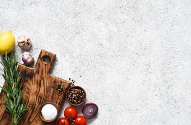 Lambada baharat ve sebze bulunan kahverengi kesim tahtası, beton mutfak masası. Düzen.