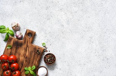 Lambada baharat ve sebze bulunan kahverengi kesim tahtası, beton mutfak masası. Düzen.