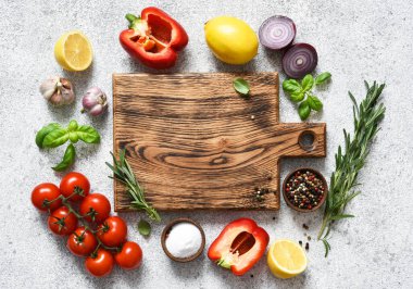 Lambada baharat ve sebze bulunan kahverengi kesim tahtası, beton mutfak masası. Düzen.