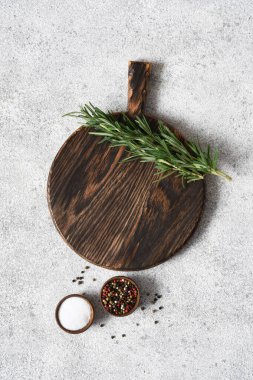 Hafif beton arka planda biberiye ve baharatlarla kesme tahtası.