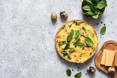 Somon ve ıspanaklı kiş, açık beton arka planda peynir. Yukarıdan görüntüle.