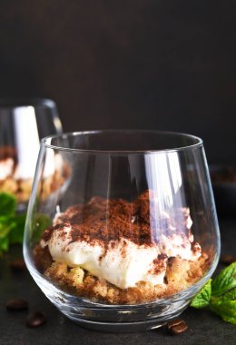 Koyu beton arka planda bir bardakta tiramisu tatlısı.