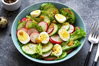 Sebzeli, turplu, yumurtalı ve salatalı taze salata. Beton arka planda mavi bir tabakta..