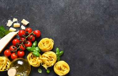 Tagliatele makarna, domates, fesleğen ve parmesan peyniri siyah beton arka planda. Makarna malzemeleri ve metin alanı. Düzen.
