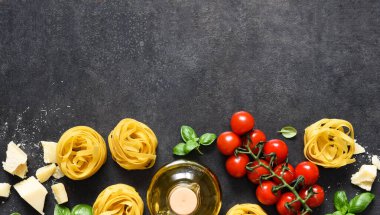 Tagliatele makarna, domates, fesleğen ve parmesan peyniri siyah beton arka planda. Makarna malzemeleri ve metin alanı. Düzen.