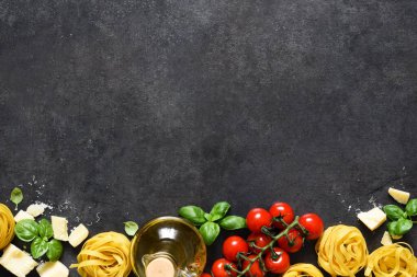 Tagliatele makarna, domates, fesleğen ve parmesan peyniri siyah beton arka planda. Makarna malzemeleri ve metin alanı. Düzen.
