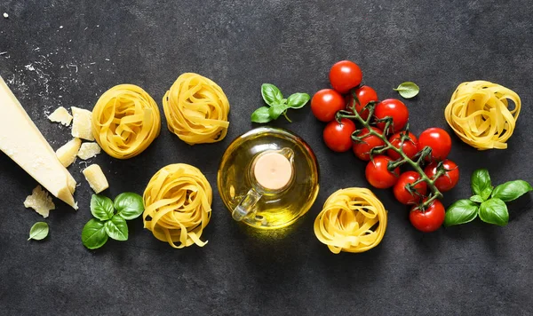 Tagliatele makarna, domates, fesleğen ve parmesan peyniri siyah beton arka planda. Makarna malzemeleri ve metin alanı. Düzen.