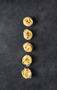 Siyah beton bir masada Tagliatelle makarnası. Mutfak masasında makarna pişirmek..