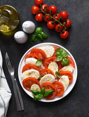 Caprese bir domates ve mozzarella aperatifi. Siyah arka planda yazılı geleneksel İtalyan salatası. Yukarıdan görüntüle.