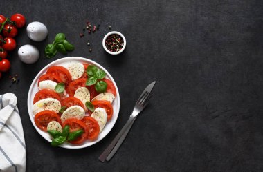 Caprese bir domates ve mozzarella aperatifi. Siyah arka planda yazılı geleneksel İtalyan salatası. Yukarıdan görüntüle.
