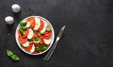 Caprese bir domates ve mozzarella aperatifi. Siyah arka planda yazılı geleneksel İtalyan salatası. Yukarıdan görüntüle.