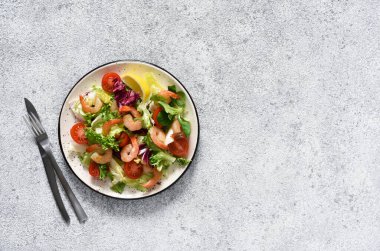 Salata, domates, ızgara karides, sos ve klemati mutfak masasında karıştırın. Yukarıdan bak. Somut gıda geçmişi.