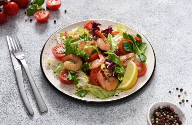 Salata, domates, ızgara karides, sos ve klemati mutfak masasında karıştırın. Somut gıda geçmişi.