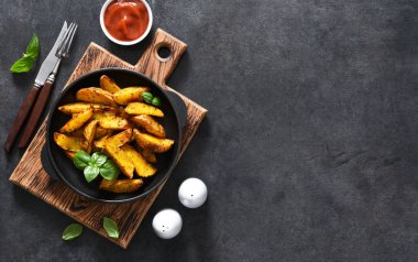 Beton bir arka planda kızartma tavasında kızarmış patates dilimleri ve sos. Fırında patates dilimleri..