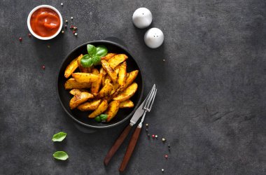 Beton bir arka planda kızartma tavasında kızarmış patates dilimleri ve sos. Fırında patates dilimleri..