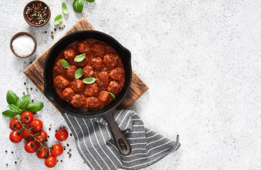 Hafif beton arka planda tavada domates soslu köfteler..