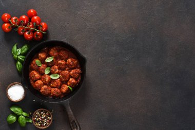 Köfteler, domates soslu, sarımsaklı ve fesleğenli kahverengi arka planda kızartma tavasında..