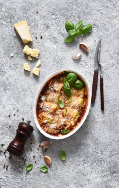 Fırında kabak ruloları, ricotta peyniri, domates sosu ve beton bir masada fesleğen. Yukarıdan görüntüle.