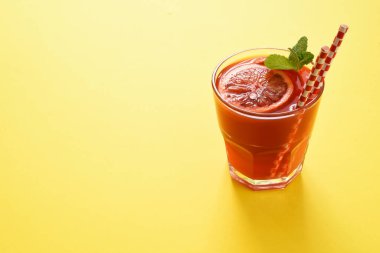 Sarı arka planda kırmızı portakal suyu. Güzel gıda konsepti, trend 2021.