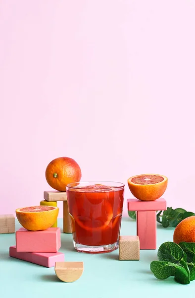 Red orange juice in a glass with geometric shapes. Pop trend 2021. The concept of beautiful food.